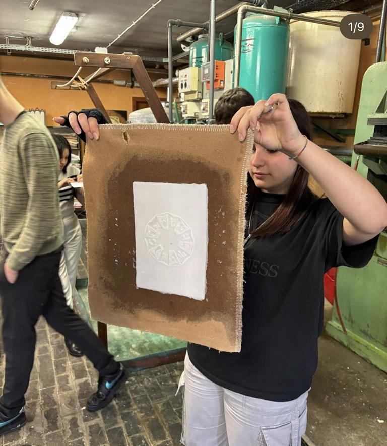 Teilnehmerin hält frisch geschöpftes Papier mit Wasserzeichen in den Händen.