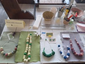 Verschiedene Schmuckstücke und Gegenstände aus Papier liegen auf einem Tisch ausgestellt.