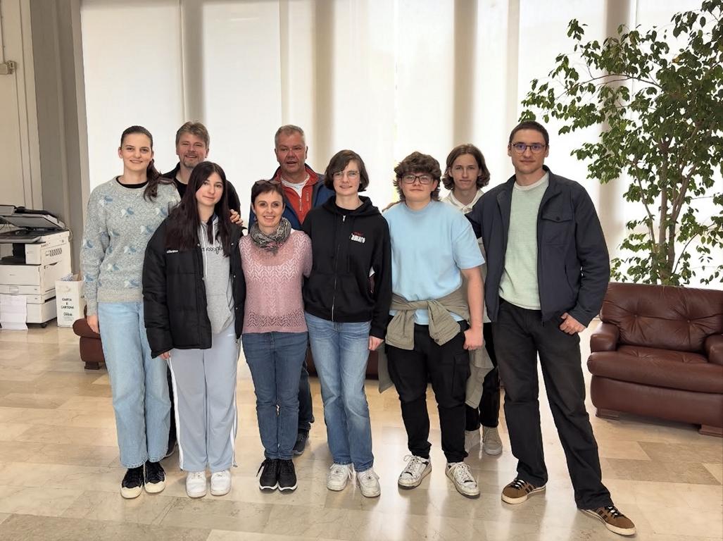 Gruppe von Schülern und Lehrkräften steht gemeinsam in einer Eingangshalle für ein Foto.