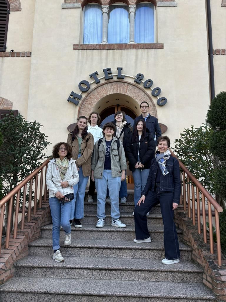 Eine Schülergruppe steht vor dem Eingang des „Hotel 2000“ in Fabriano auf einer Treppe und blickt in die Kamera