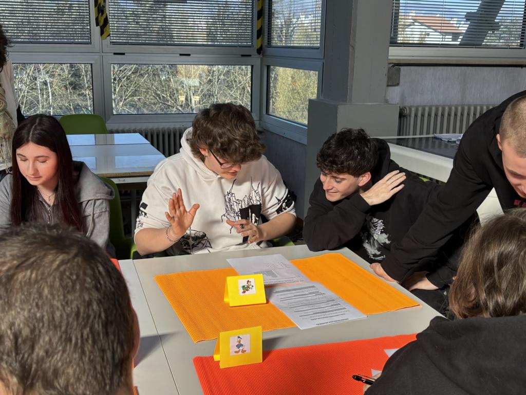 Mehrere Teilnehmende sitzen gemeinsam an einem Tisch und bearbeiten eine Aufgabe im Unterricht.